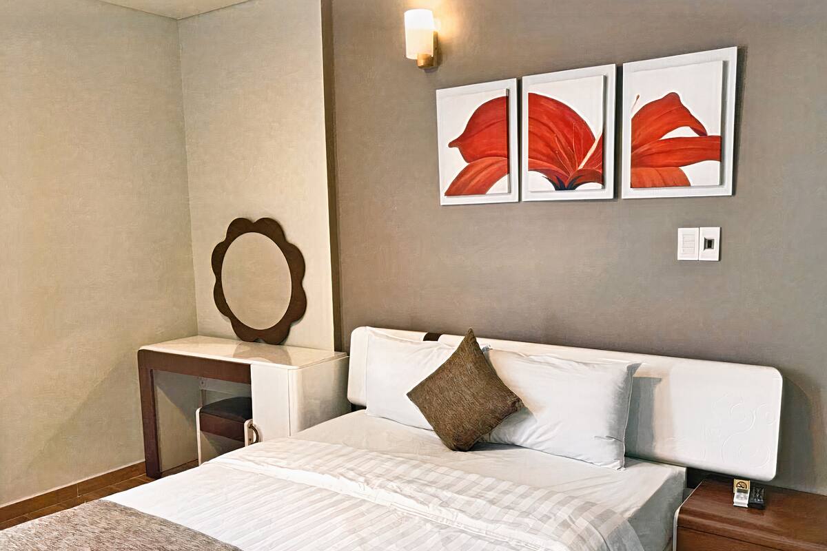 Ein Hotelzimmer mit Bett, Nachttisch, Schreibtisch und Wandbildern.