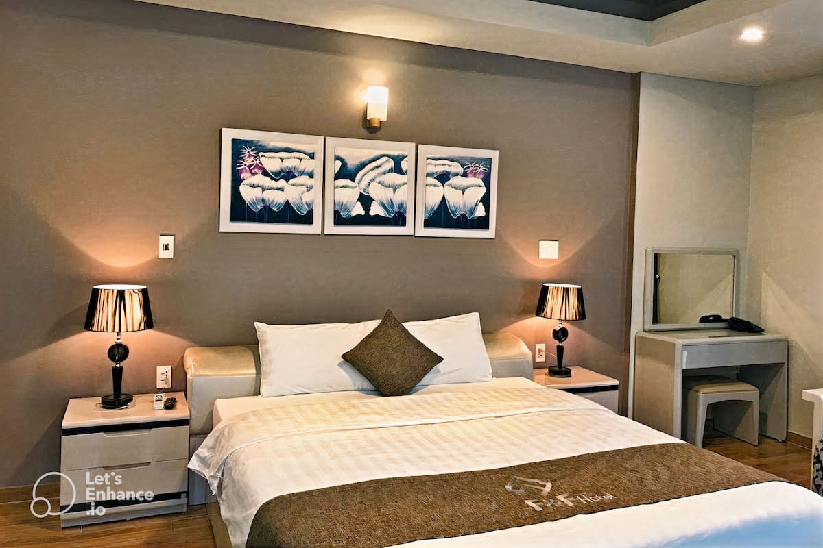 Ein Hotelzimmer mit einem Bett, zwei Nachttischen, einem Fernseher und Bildern an der Wand.