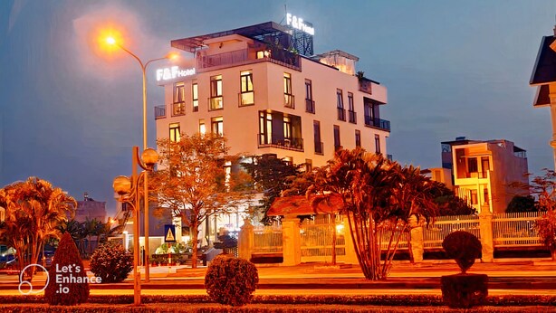 A hotel with a modern design, featuring a balcony on the upper floor, a well-lit entrance, and a landscaped garden area. - F&F Hotel (Hai Phong)
