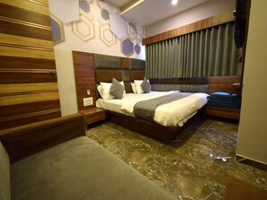 A bedroom with a bed, a nightstand, a wooden headboard, and a curtain. - The Lake Palace (Ahmedabad)