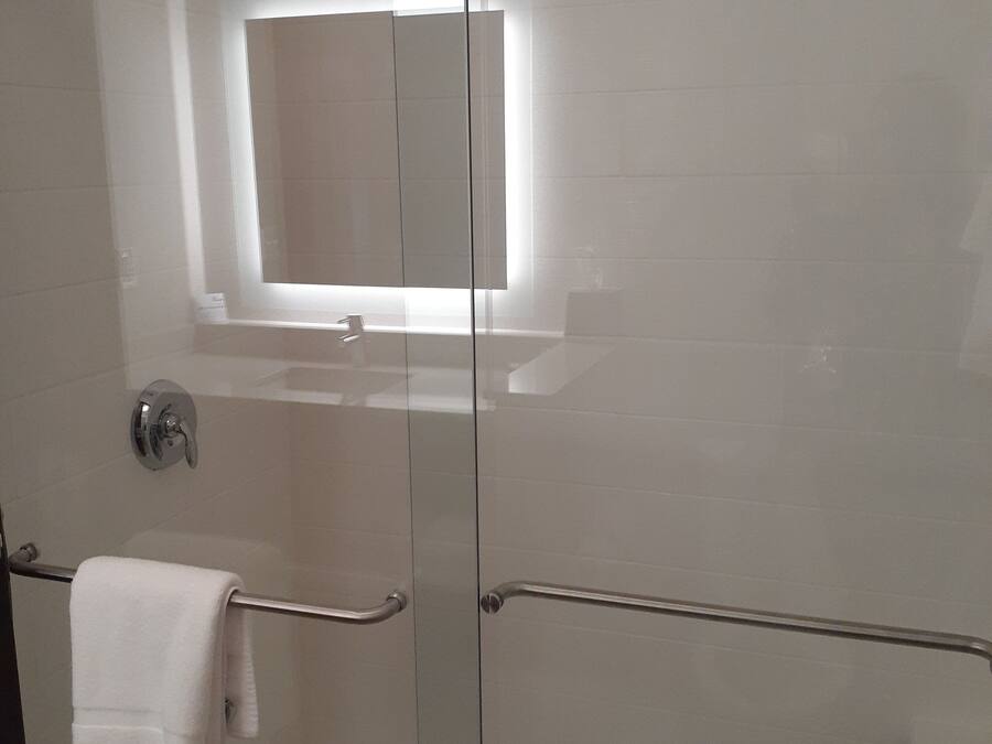 A glass-enclosed shower with a white towel hanging on a metal handle.