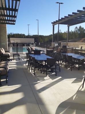 An outdoor patio area with tables and chairs, a pool, and a pergola structure. - Holiday Inn Express Richburg by IHG (Richburg)