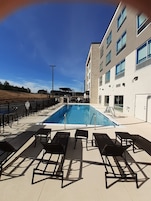 Una piscina al aire libre, sillones reclinables de piscina