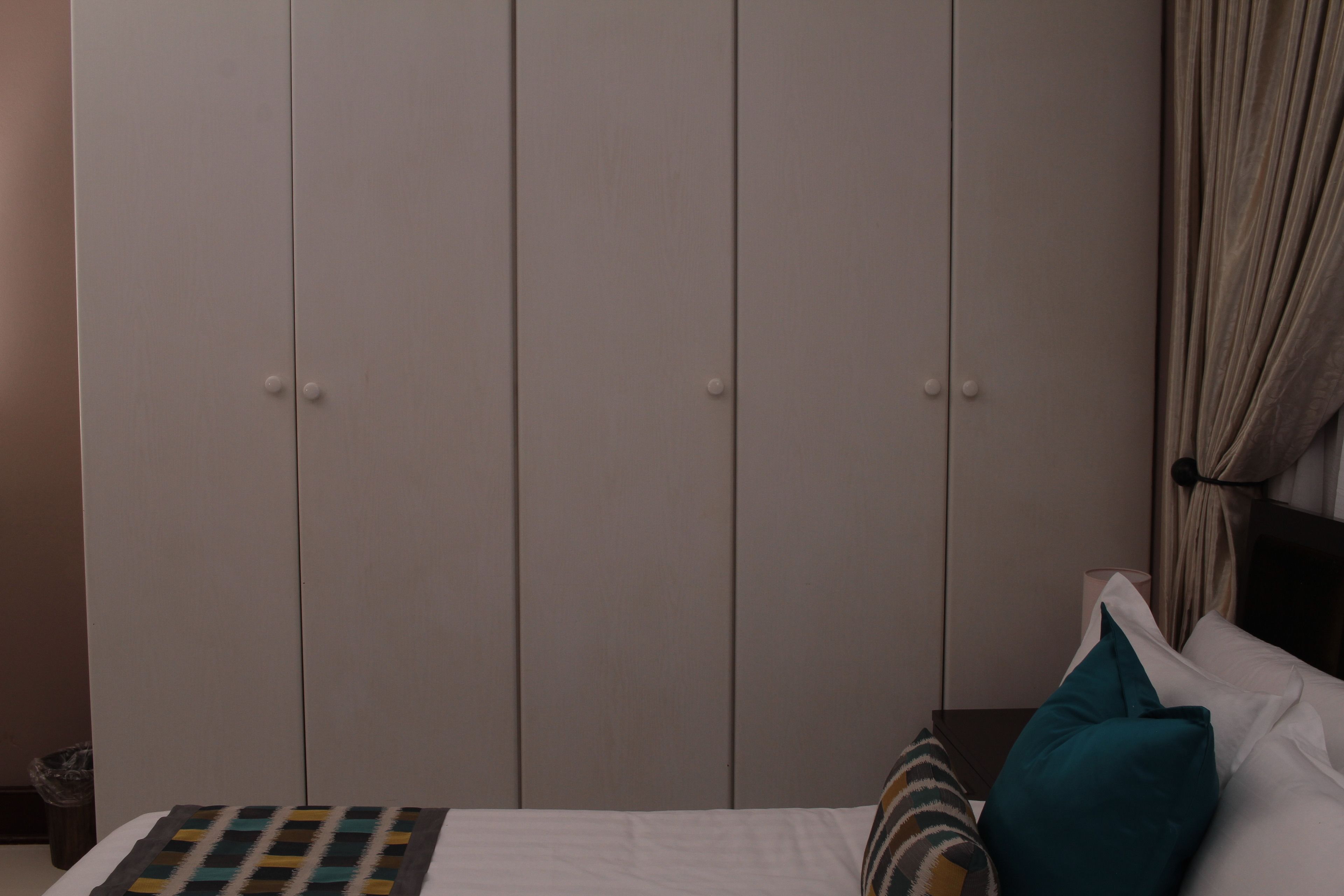 Un dormitorio con cama, almohadas, mesita de noche y armario.