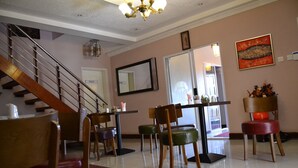 A dining area with a staircase, a mirror, and a red patterned rug. - Triple Palms Bed and Breakfast (Gaborone)