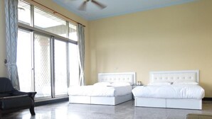 Une chambre d’hôtel avec deux lits, un ventilateur de plafond et de grandes fenêtres avec des rideaux.