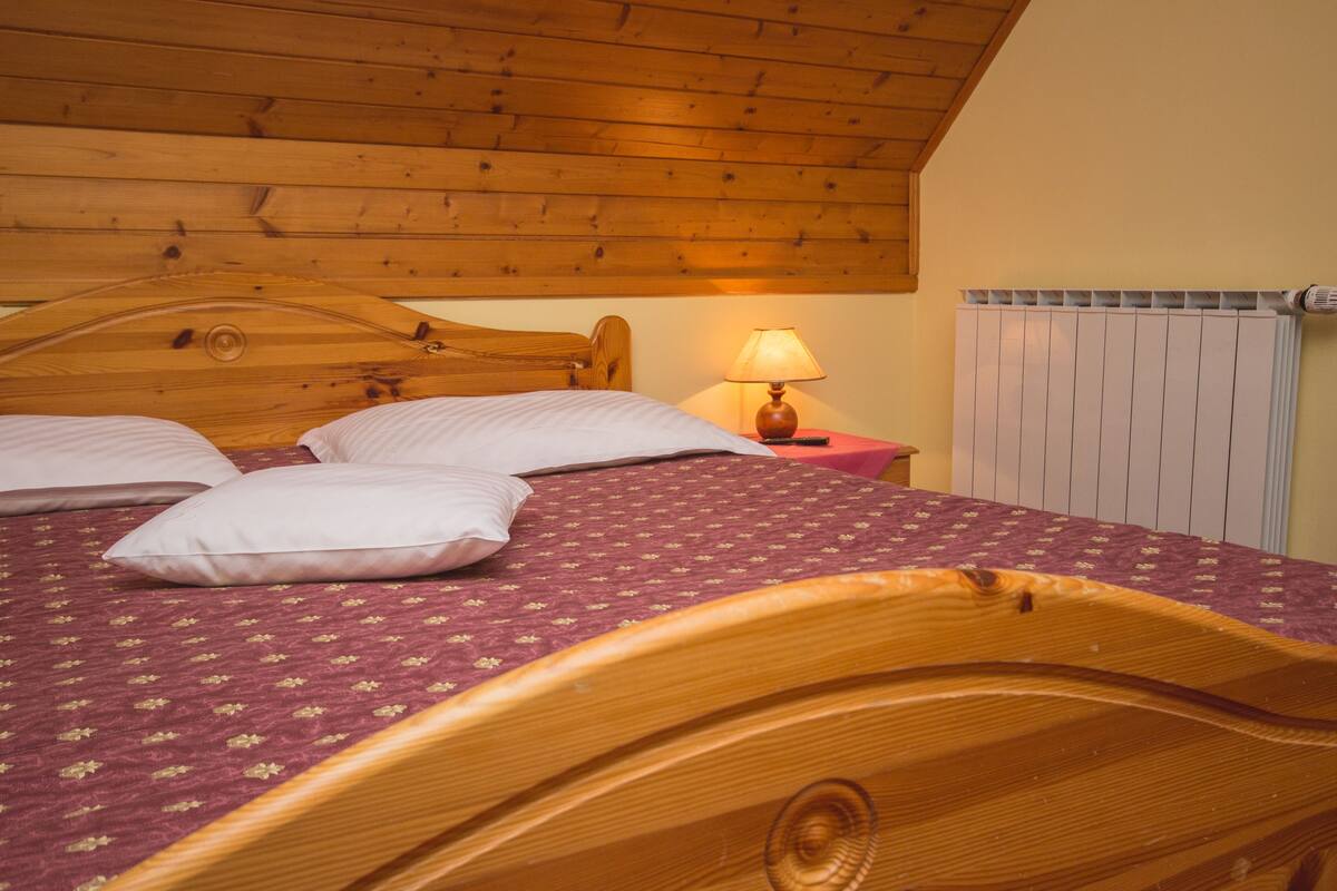 A wooden bed with a headboard, a bedside lamp, and a radiator.