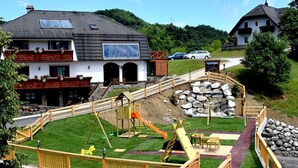 Un parque infantil con toboganes y estructuras para escalar, rodeado de bancos de madera y mesas de picnic.