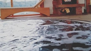 Una habitación con bañera de hidromasaje, chimenea y un amplio ventanal con vistas.