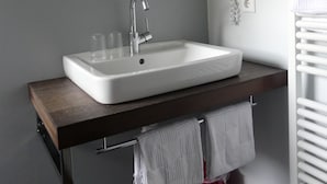 Un baño moderno con un lavamanos blanco, un espejo y un perchero para toallas.