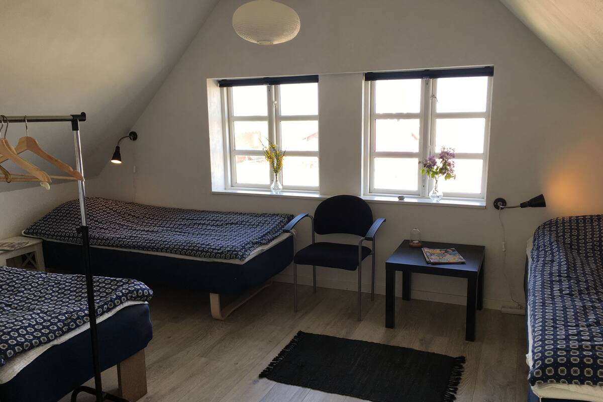 Ein Schlafsaalzimmer mit zwei Betten, einem Schreibtisch, einem Stuhl und einem Fenster mit Aussicht.