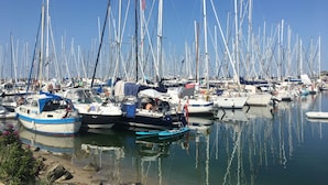 Un port de plaisance où sont amarrés de nombreux voiliers, avec une eau calme et un ciel dégagé.