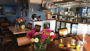 Un restaurant avec des tables et des chaises en bois, et un vase de fleurs posé sur la table.