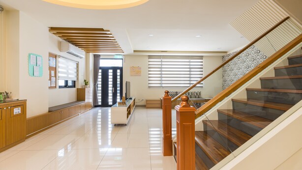 A spacious lobby with a wooden staircase, a reception desk, and a seating area. - Jialai Homestay (Magong)