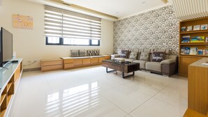 A modern living room with a sofa, coffee table, and a television. - Jialai Homestay (Magong)
