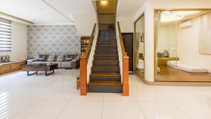 A modern living room with a wooden staircase, a sofa set, and a glass partition leading to a bedroom. - Jialai Homestay (Magong)