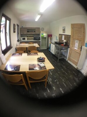 A compact kitchen with a dining area, equipped with basic appliances and a refrigerator. - Zimmerfrei (Wuppertal)