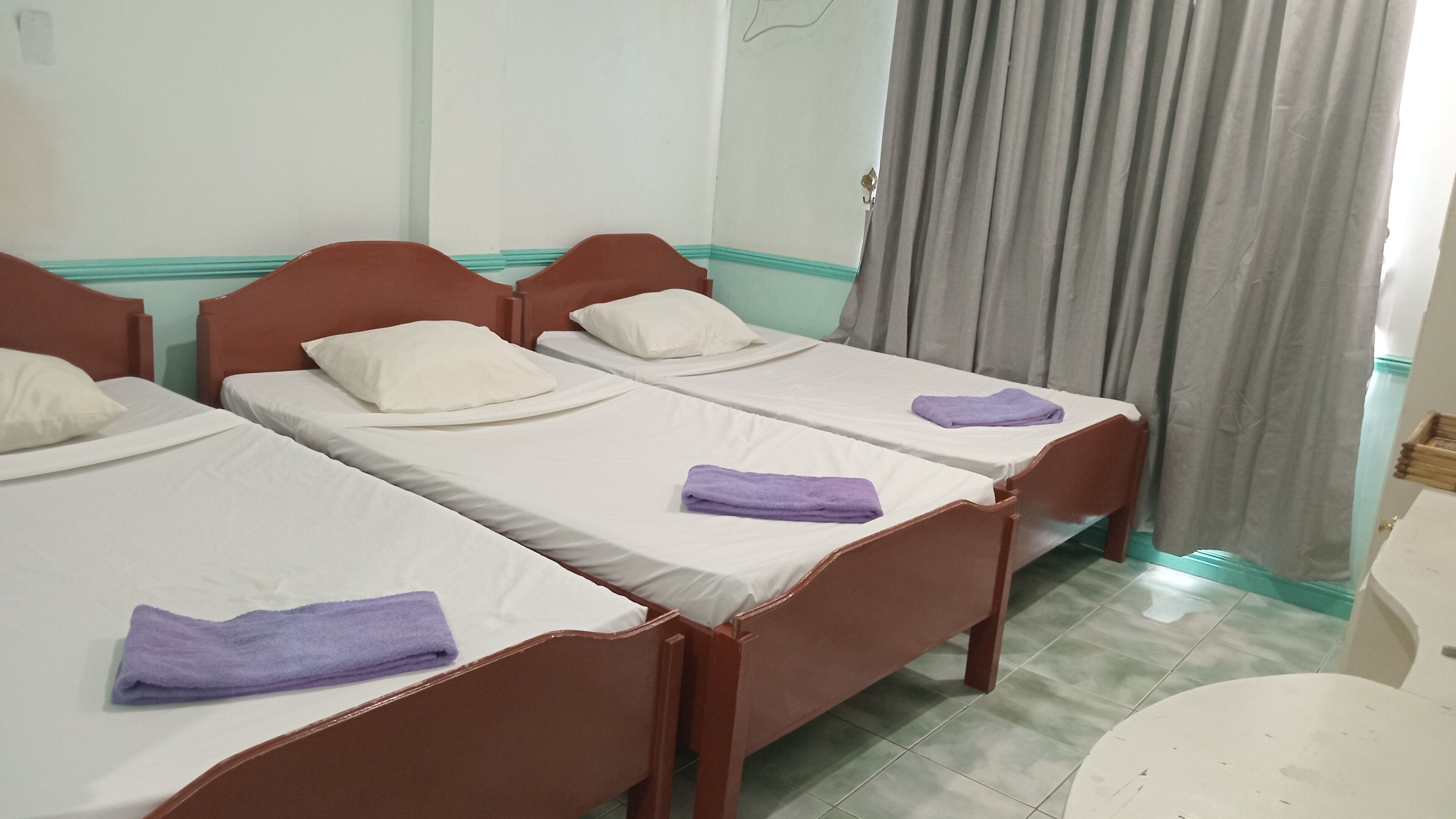 Quarto com duas camas de solteiro, cada uma com travesseiro e toalha dobrada.