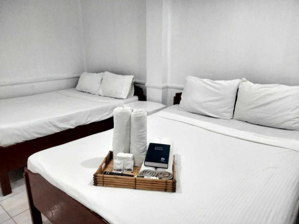 Ein Hotelzimmer mit zwei Einzelbetten, einem Nachttisch mit Pflegeartikeln und einer Ablage mit Handtüchern und einem Buch.