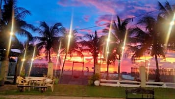Vista de un atardecer con palmeras y mesas al aire libre.