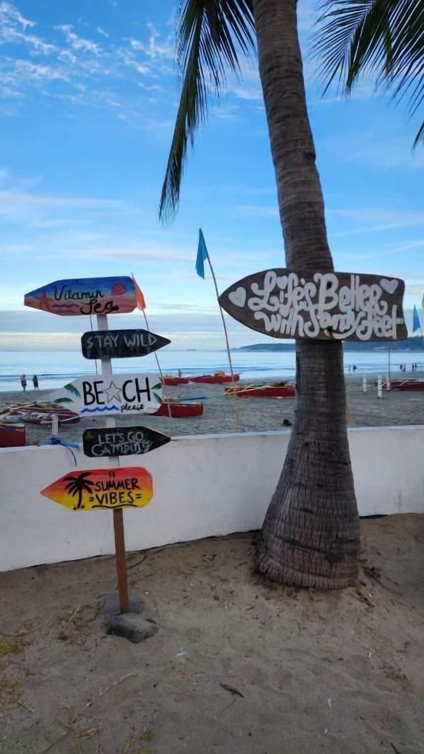 Un panneau indicateur sur la plage, muni de plusieurs flèches indiquant différentes directions.