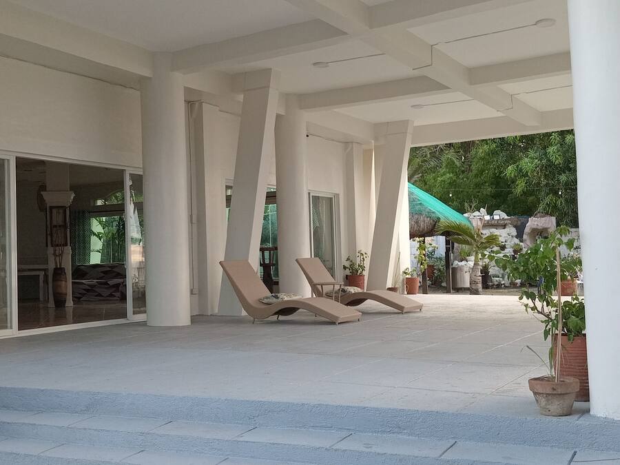 Un espacio al aire libre con sillones de descanso y plantas en macetas.