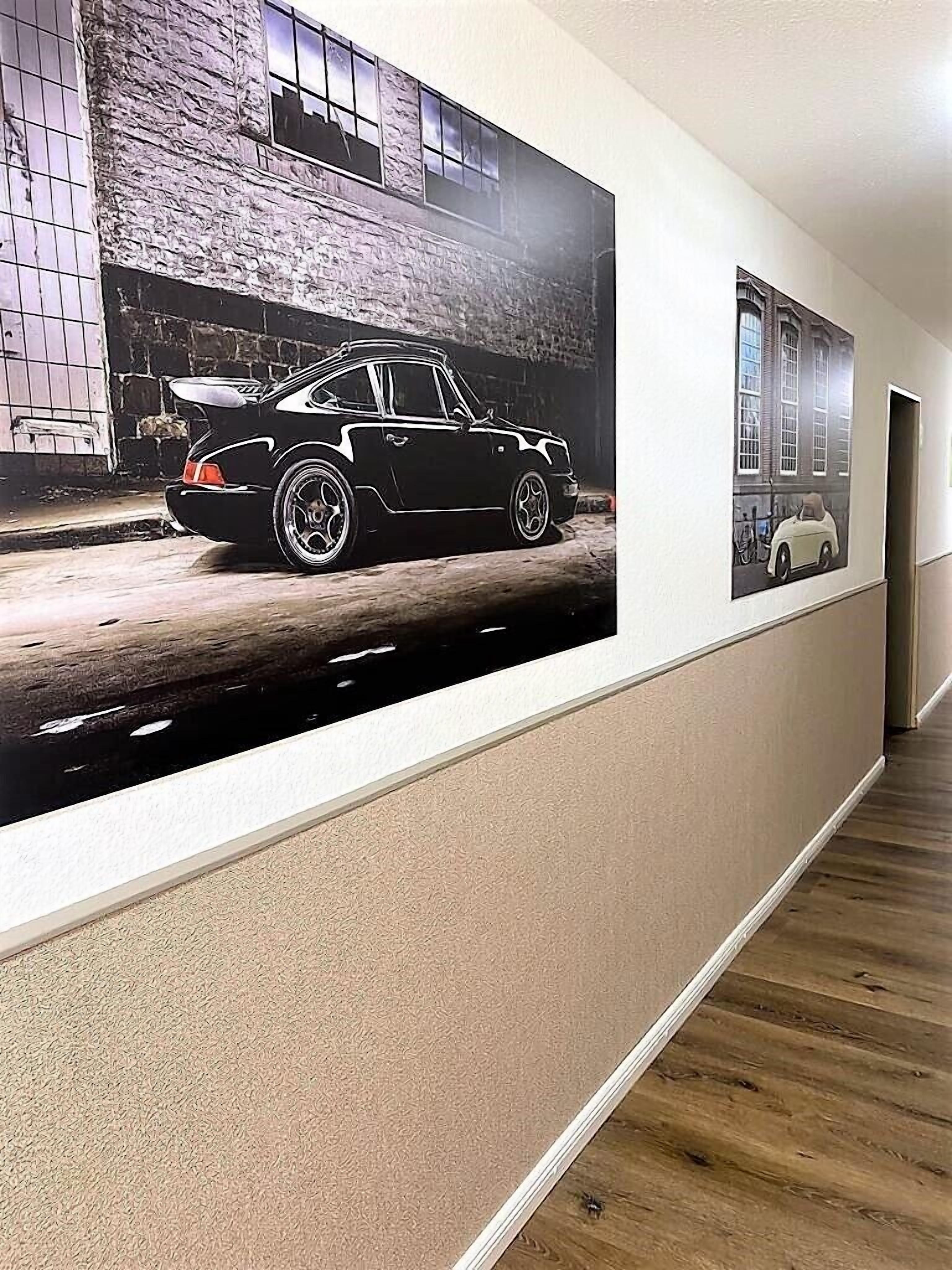 A hallway with a large poster of a car on the wall and a door at the end.