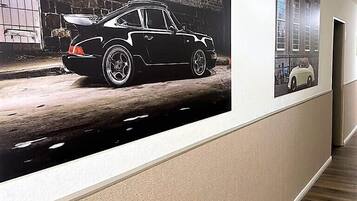 A hallway with a large poster of a car on the wall and a door at the end.
