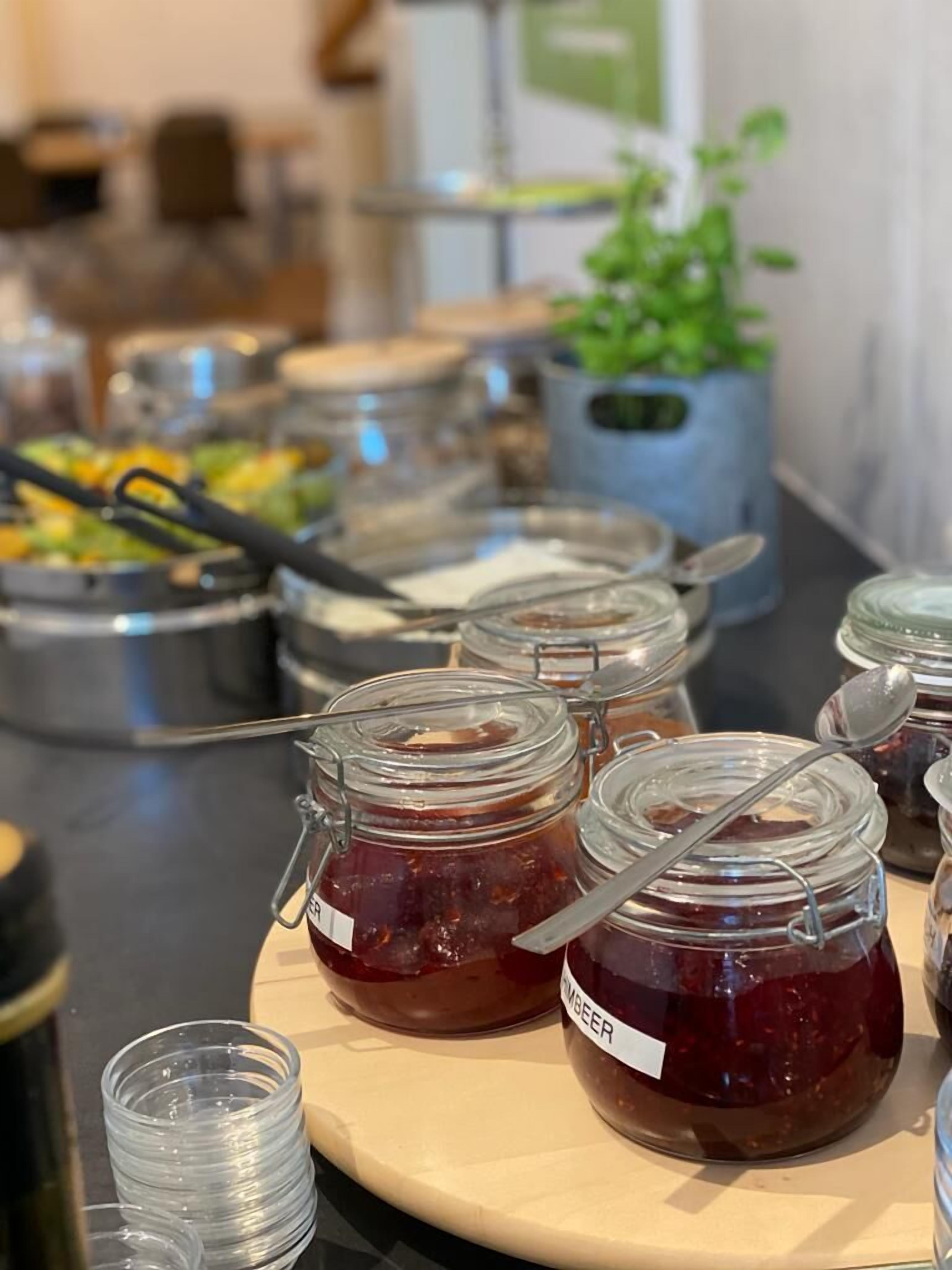 A buffet table with various food items and condiments, including jars of jam labeled 'GUMBEER'.