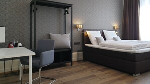 A modern hotel room with a large bed, a desk, and a chair.