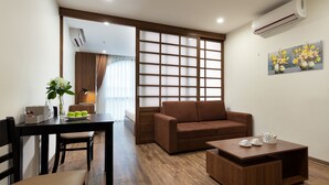 Un salon moderne avec un canapé marron, une table basse en bois et un coin repas comprenant une table et des chaises.