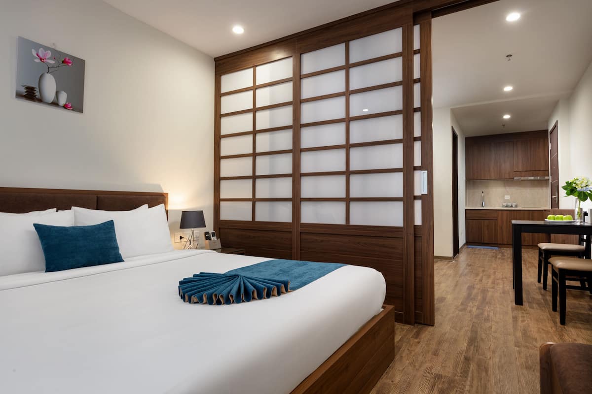 Una habitación de hotel con cama, escritorio y kitchenette.