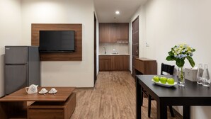 Une cuisine moderne avec des meubles en bois, un téléviseur encastré et un coin repas avec une table mise pour trois personnes.