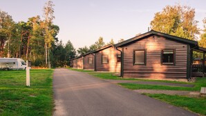A row of wooden cabins with a paved driveway leading to them, surrounded by trees.