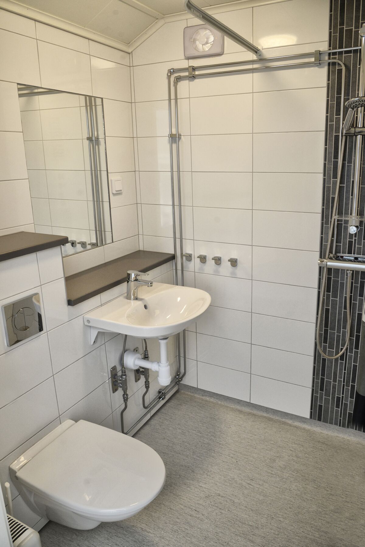 Casa de banho pequena e moderna com lavatório branco, sanita e zona de duche.