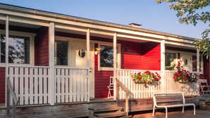 A red house with white trim, a porch with steps, and a bench.