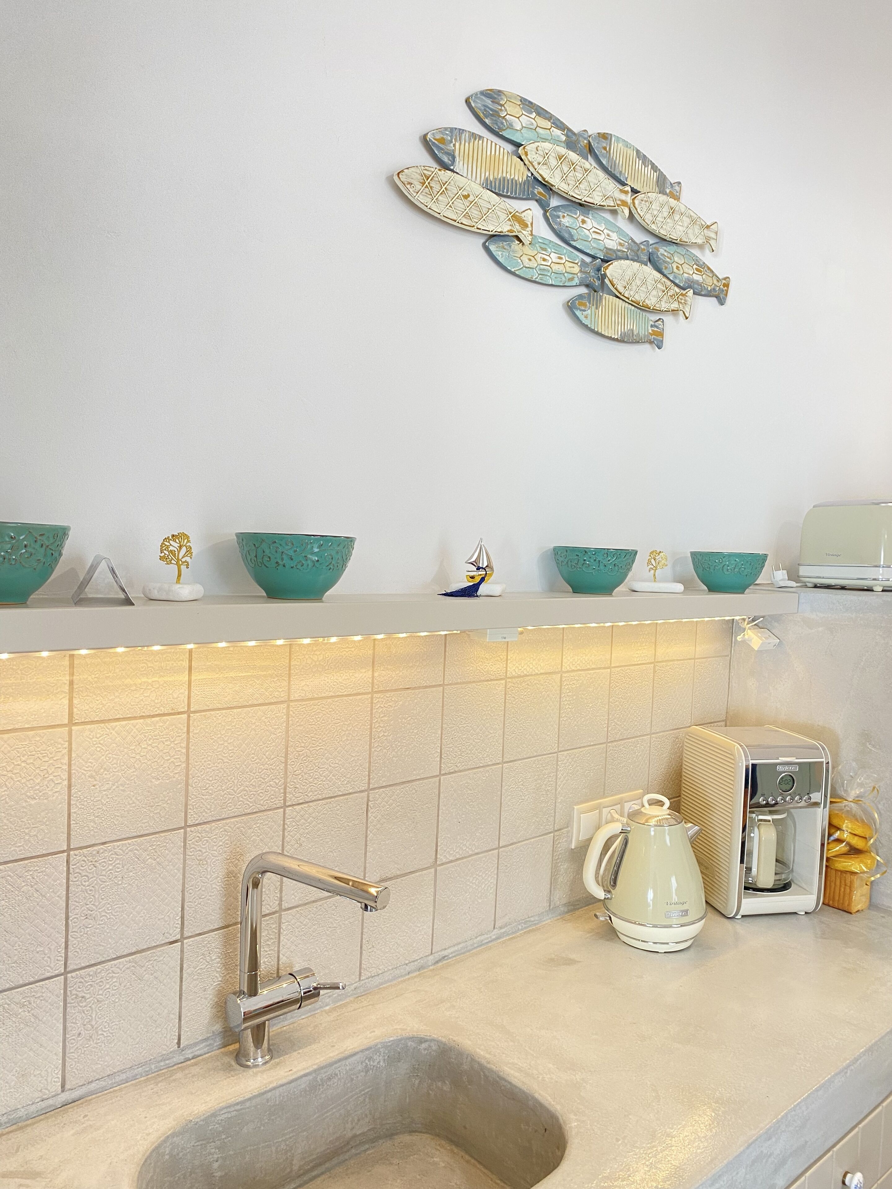 Une cuisine équipée d’un évier, d’une machine à café et de quelques objets décoratifs posés sur le plan de travail.