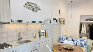 A modern kitchen with a coffee machine, a sink, and a dining area with a round wooden table and two chairs.