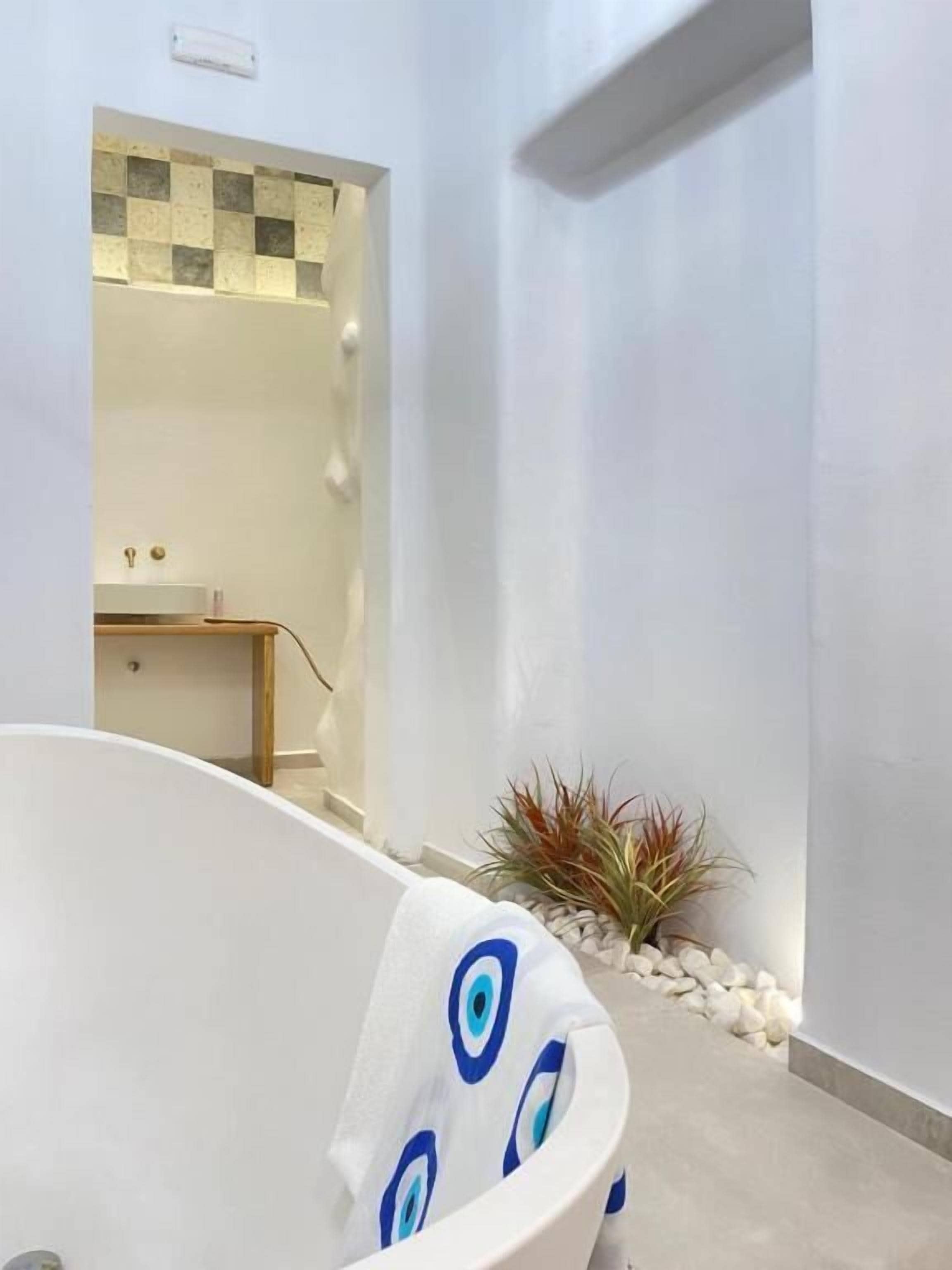 Un baño moderno con una bañera independiente, un lavamanos pequeño y un espejo encima.