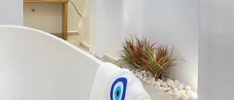 Un baño moderno con una bañera independiente, un lavamanos pequeño y un espejo encima.