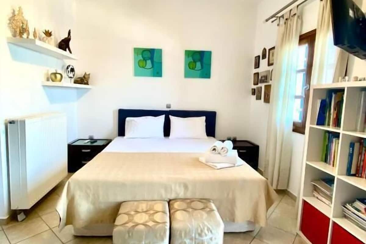 A hotel room with a bed, bedside tables, a bookshelf, a radiator, and a hanging light fixture.