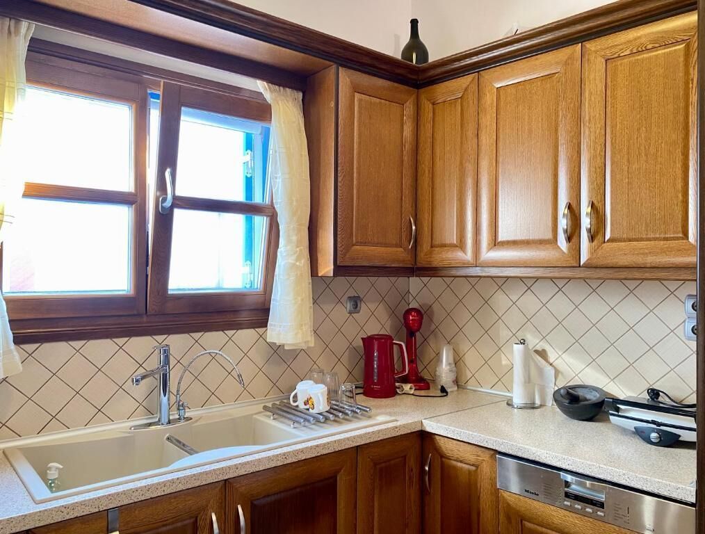 A kitchen with wooden cabinets, a sink, a coffee maker, and a kettle.