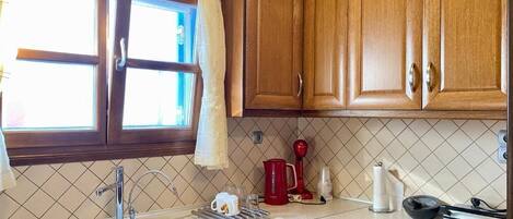 A kitchen with wooden cabinets, a sink, a coffee maker, and a kettle.