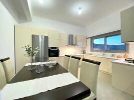 Una cocina moderna con una mesa de comedor para cuatro personas, equipada con refrigerador, horno y microondas.