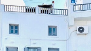 A white building with multiple windows, a balcony, and an air conditioning unit.