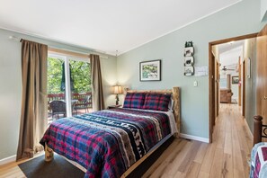 Une chambre à coucher avec un lit, une fenêtre avec des rideaux, une porte et une vue sur un espace extérieur.