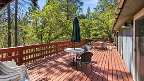Eine Holzterrasse mit Gartenmöbeln, einem Tisch und Stühlen sowie einem grünen Sonnenschirm.