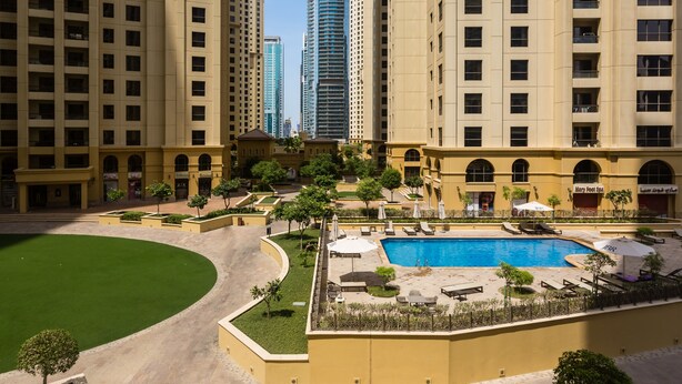 A hotel with a swimming pool, outdoor seating, and a courtyard. - HiGuests - Sadaf 6 (Dubai)