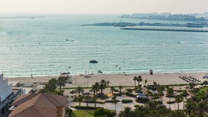 A coastal view with a beach, palm trees, and a bridge in the background. - HiGuests - Sadaf 6 (Dubai)
