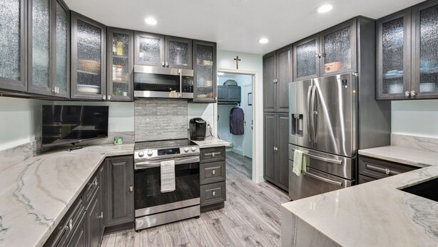 A modern kitchen with dark cabinets, a central island with an oven, a refrigerator, and a microwave. - San Clemente / Dana Point- (San Clemente)